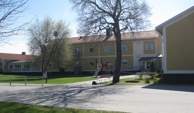 Hållnäs gula skolbyggnad och skolgård.