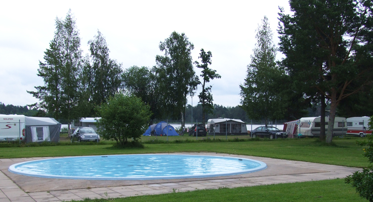 Ängskärs camping med pool i förgrunden och husvagnar i bakgrunden.