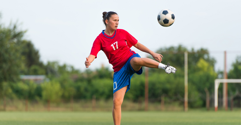 Kvinnlig fotbollsspelare sparkar på en boll.