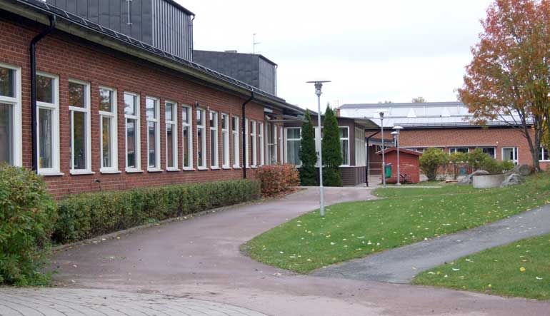 Aspenskolans huvudingång med gräsmatta i förgrunden