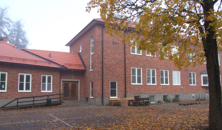Vendels skolas huvudentré med skolgård dekorerad med höstlöv.
