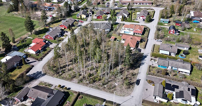 Drönarbild över aktuell tomt i Skärplinge med grönytor, hustak och gator.