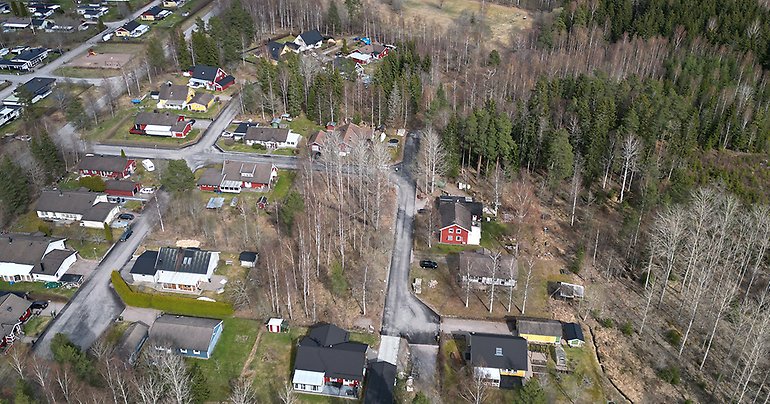 Drönarbild över aktuell tomt i Söderfors med grönytor, hustak och gator.