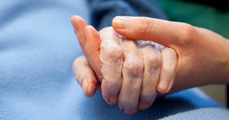 En yngre hand håller i en åldrad hand. 