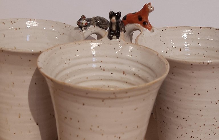 Tre keramikmuggar med små katter på